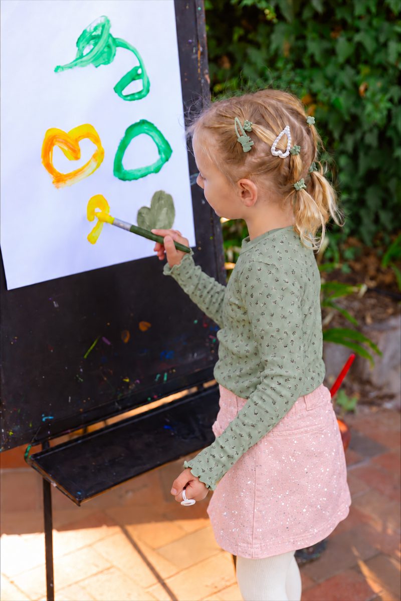 A young girl painting hearts at an easel